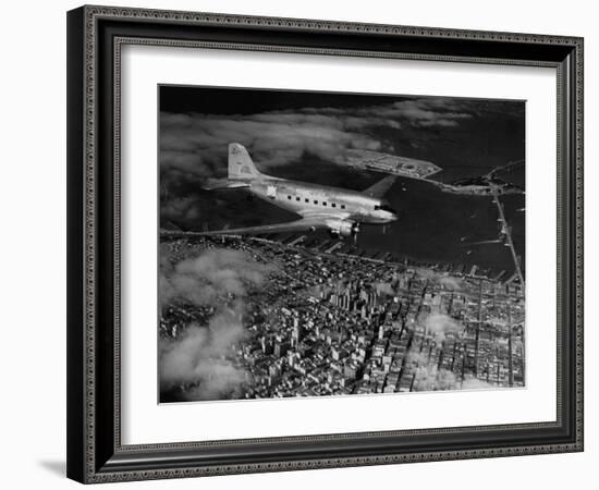 Plane Flying over a City from a Story Concerning United Airlines-Carl Mydans-Framed Photographic Print