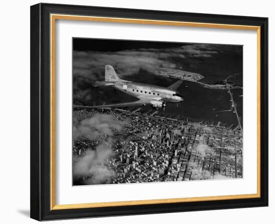 Plane Flying over a City from a Story Concerning United Airlines-Carl Mydans-Framed Photographic Print