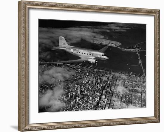 Plane Flying over a City from a Story Concerning United Airlines-Carl Mydans-Framed Photographic Print