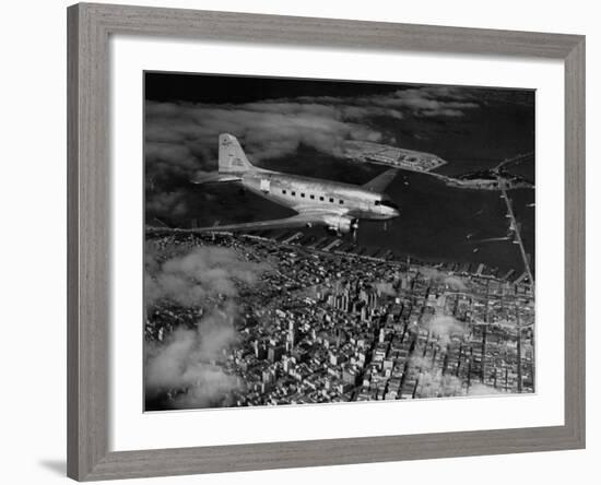 Plane Flying over a City from a Story Concerning United Airlines-Carl Mydans-Framed Photographic Print