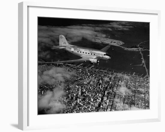 Plane Flying over a City from a Story Concerning United Airlines-Carl Mydans-Framed Photographic Print