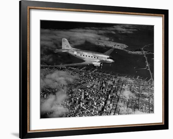 Plane Flying over a City from a Story Concerning United Airlines-Carl Mydans-Framed Photographic Print