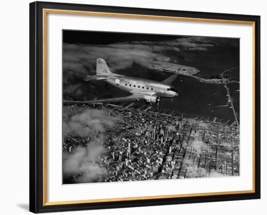 Plane Flying over a City from a Story Concerning United Airlines-Carl Mydans-Framed Photographic Print