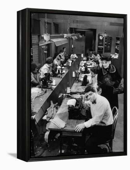 Playwright Paddy Chayefsky Sitting at Typewriter in Garment Factory With Workers on Sewing Machines-Michael Rougier-Framed Premier Image Canvas