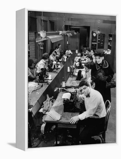 Playwright Paddy Chayefsky Sitting at Typewriter in Garment Factory With Workers on Sewing Machines-Michael Rougier-Framed Premier Image Canvas