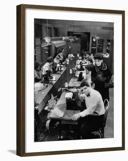 Playwright Paddy Chayefsky Sitting at Typewriter in Garment Factory With Workers on Sewing Machines-Michael Rougier-Framed Premium Photographic Print
