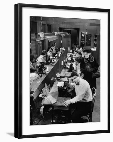 Playwright Paddy Chayefsky Sitting at Typewriter in Garment Factory With Workers on Sewing Machines-Michael Rougier-Framed Premium Photographic Print