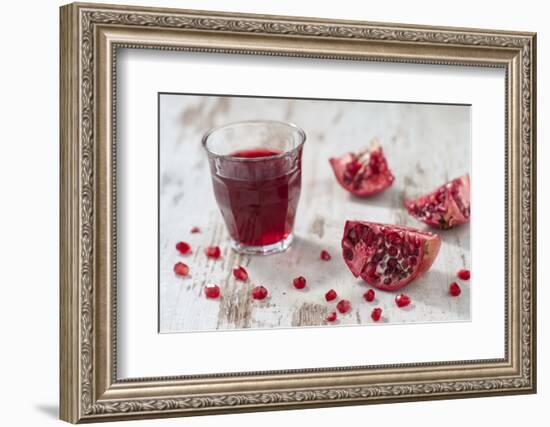 Pomegranate Pieces and a Glass of Pomegranate Juice on White Wooden Table-Jana Ihle-Framed Photographic Print