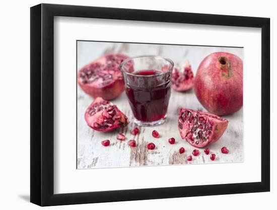 Pomegranates and Glass with Pomegranate Juice on White Wooden Table-Jana Ihle-Framed Photographic Print