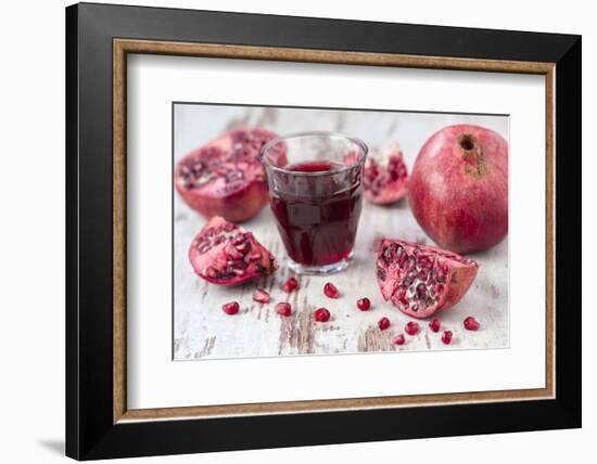 Pomegranates and Glass with Pomegranate Juice on White Wooden Table-Jana Ihle-Framed Photographic Print