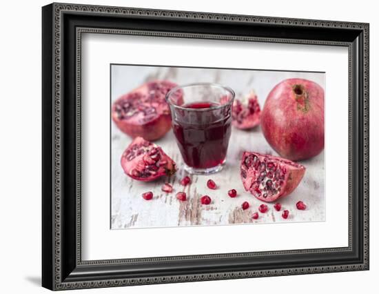 Pomegranates and Glass with Pomegranate Juice on White Wooden Table-Jana Ihle-Framed Photographic Print