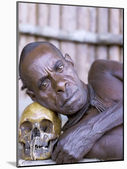 Portrait of an Asmat Tribesman Leaning on a Human Skull, Irian Jaya, Indonesia-Claire Leimbach-Mounted Photographic Print