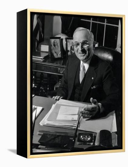 Pres. Harry S. Truman Seated at His Desk in the White House, Family Photographs on Table Behind Him-Gjon Mili-Framed Premier Image Canvas