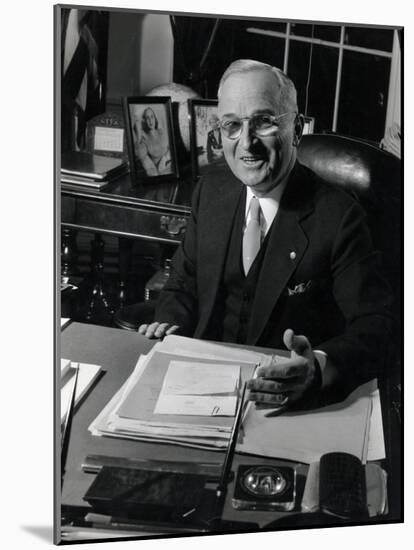 Pres. Harry S. Truman Seated at His Desk in the White House, Family Photographs on Table Behind Him-Gjon Mili-Mounted Photographic Print