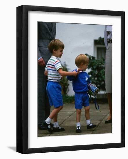 Prince Harry wearing a blue sweatshirt shorts and thomas the tank engine bag with Prince William on-null-Framed Photographic Print