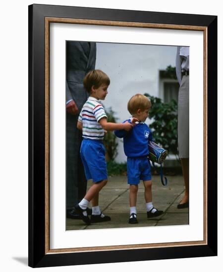 Prince Harry wearing a blue sweatshirt shorts and thomas the tank engine bag with Prince William on-null-Framed Photographic Print