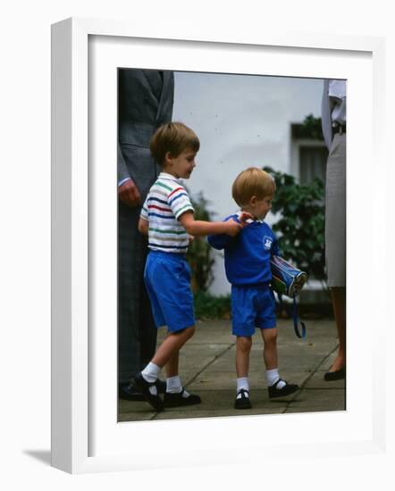 Prince Harry wearing a blue sweatshirt shorts and thomas the tank engine bag with Prince William on-null-Framed Photographic Print