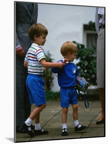 Prince Harry wearing a blue sweatshirt shorts and thomas the tank engine bag with Prince William on-null-Mounted Photographic Print