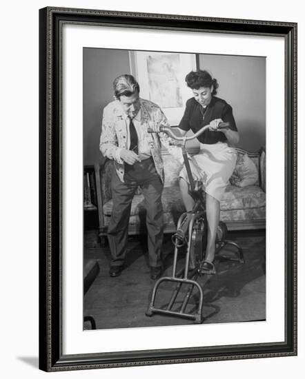 Producer-Director Preston Sturges and His Secretary Trying Out an Exercise Bicycle-John Florea-Framed Premium Photographic Print