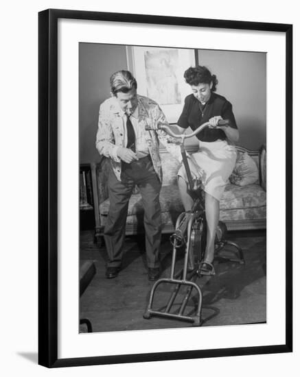 Producer-Director Preston Sturges and His Secretary Trying Out an Exercise Bicycle-John Florea-Framed Premium Photographic Print