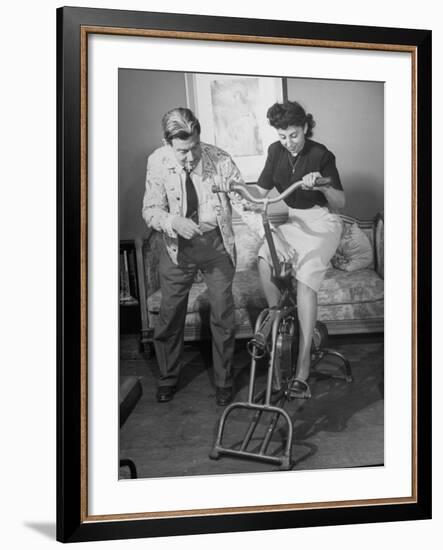 Producer-Director Preston Sturges and His Secretary Trying Out an Exercise Bicycle-John Florea-Framed Premium Photographic Print