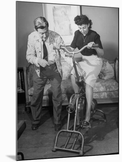Producer-Director Preston Sturges and His Secretary Trying Out an Exercise Bicycle-John Florea-Mounted Premium Photographic Print
