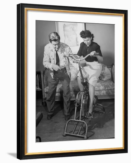 Producer-Director Preston Sturges and His Secretary Trying Out an Exercise Bicycle-John Florea-Framed Premium Photographic Print