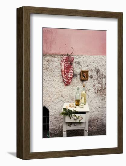 Raw Pork Ribs Hanging on the Wall of a House, Next to a A Gold-Framed Picture-Maria Brinkop-Framed Photographic Print