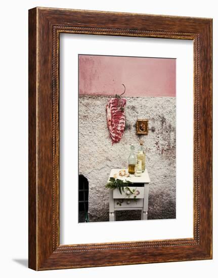 Raw Pork Ribs Hanging on the Wall of a House, Next to a A Gold-Framed Picture-Maria Brinkop-Framed Photographic Print