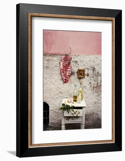 Raw Pork Ribs Hanging on the Wall of a House, Next to a A Gold-Framed Picture-Maria Brinkop-Framed Photographic Print