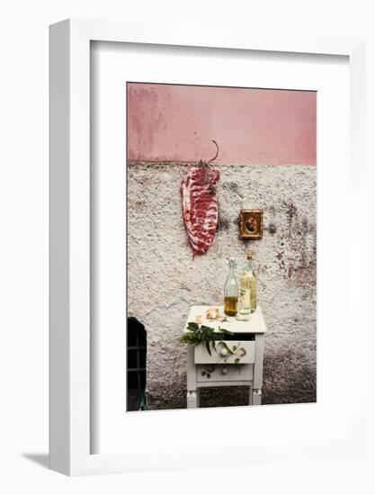 Raw Pork Ribs Hanging on the Wall of a House, Next to a A Gold-Framed Picture-Maria Brinkop-Framed Photographic Print