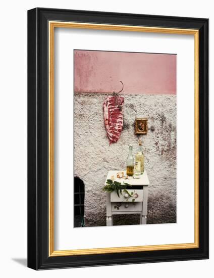 Raw Pork Ribs Hanging on the Wall of a House, Next to a A Gold-Framed Picture-Maria Brinkop-Framed Photographic Print