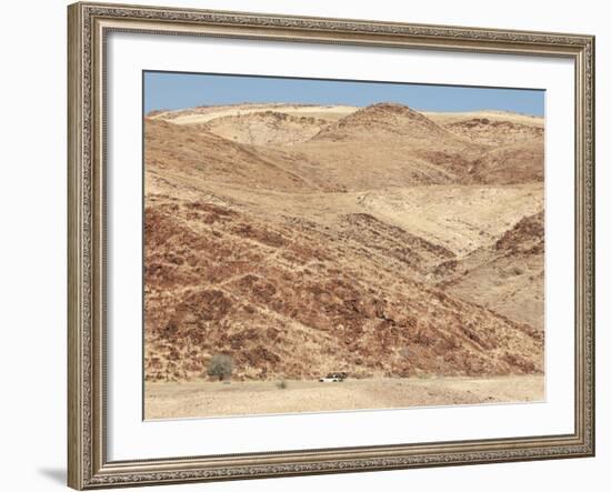 Red Rocky Landscape with Jeep in Distance, Purros Conservancy Wilderness, Kaokoland, Namibia-Kim Walker-Framed Photographic Print
