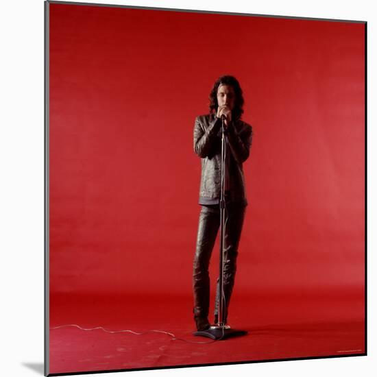 Rock Star Jim Morrison of the Doors Holding Microphone Alone as He Stands Against a Red Backdrop-Yale Joel-Mounted Premium Photographic Print