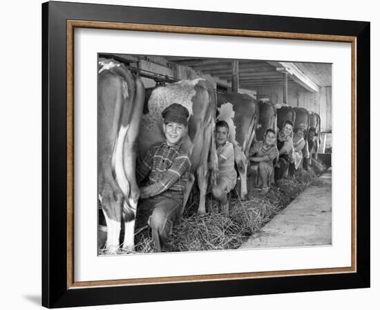 Row of Cows' Rumps, with Fat Cheeked Family of Six Milking Them, in Neat Cow Barn-Alfred Eisenstaedt-Framed Photographic Print