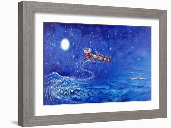 Santa in Night Sky over Winter Village in Sleigh Pulled by Reindeer-Bill Bell-Framed Giclee Print