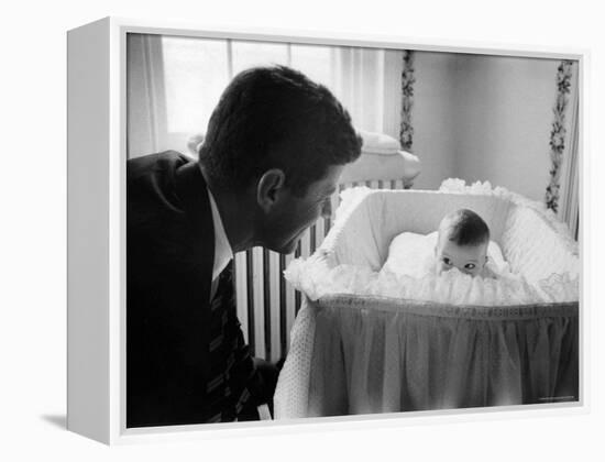 Sen. Jack Kennedy Admiring Baby Caroline as She Lies in Her Crib in Nursery at Georgetown Home-Ed Clark-Framed Premier Image Canvas