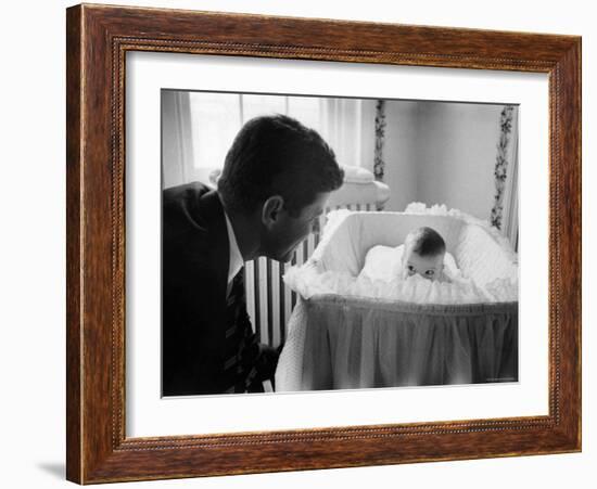 Sen. Jack Kennedy Admiring Baby Caroline as She Lies in Her Crib in Nursery at Georgetown Home-Ed Clark-Framed Photographic Print