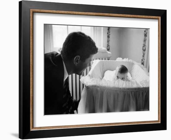 Sen. Jack Kennedy Admiring Baby Caroline as She Lies in Her Crib in Nursery at Georgetown Home-Ed Clark-Framed Photographic Print