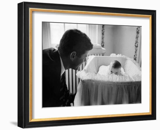 Sen. Jack Kennedy Admiring Baby Caroline as She Lies in Her Crib in Nursery at Georgetown Home-Ed Clark-Framed Photographic Print