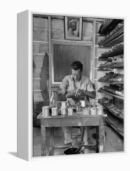 Shoemaker Sitting in His Shop Working on a Pair of Old Work Shoes-John Phillips-Framed Premier Image Canvas