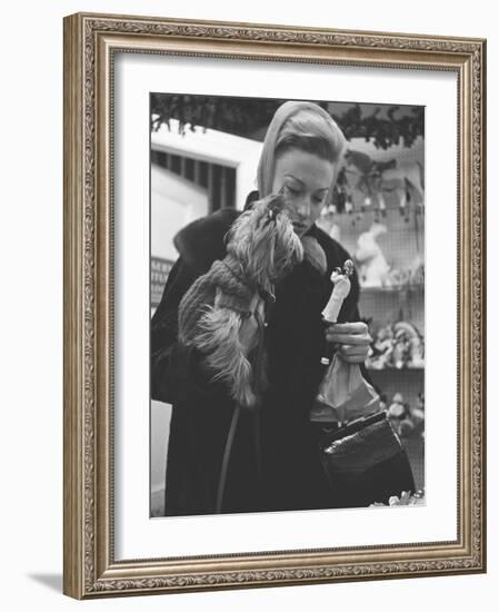 Shopper Looking at Tiny Figurine as She Holds Her Yorkshire Terrier in Arms at Saks Fifth Avenue-Yale Joel-Framed Photographic Print