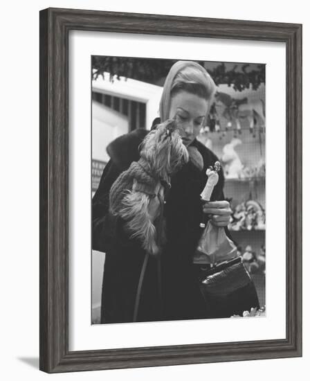 Shopper Looking at Tiny Figurine as She Holds Her Yorkshire Terrier in Arms at Saks Fifth Avenue-Yale Joel-Framed Photographic Print