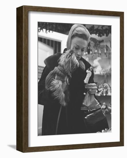 Shopper Looking at Tiny Figurine as She Holds Her Yorkshire Terrier in Arms at Saks Fifth Avenue-Yale Joel-Framed Photographic Print