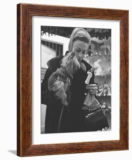 Shopper Looking at Tiny Figurine as She Holds Her Yorkshire Terrier in Arms at Saks Fifth Avenue-Yale Joel-Framed Photographic Print