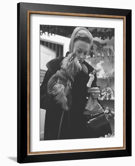 Shopper Looking at Tiny Figurine as She Holds Her Yorkshire Terrier in Arms at Saks Fifth Avenue-Yale Joel-Framed Photographic Print