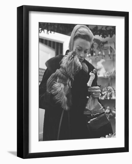 Shopper Looking at Tiny Figurine as She Holds Her Yorkshire Terrier in Arms at Saks Fifth Avenue-Yale Joel-Framed Photographic Print