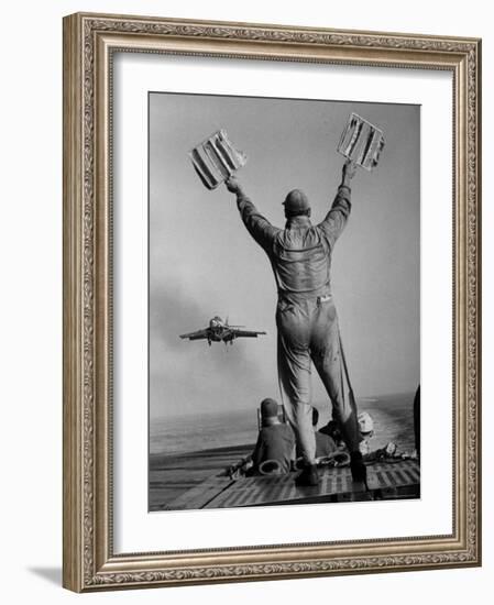 Shot of a Man Using Hand Lights to Signal an Incoming Aircraft Towards the Carrier's Landing-Hank Walker-Framed Photographic Print