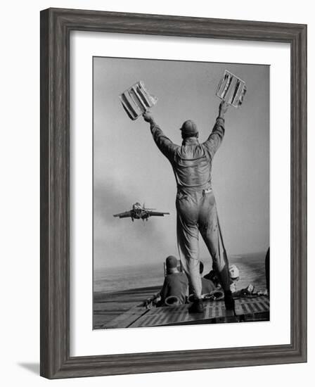 Shot of a Man Using Hand Lights to Signal an Incoming Aircraft Towards the Carrier's Landing-Hank Walker-Framed Photographic Print