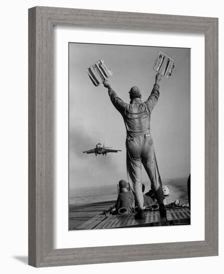 Shot of a Man Using Hand Lights to Signal an Incoming Aircraft Towards the Carrier's Landing-Hank Walker-Framed Photographic Print